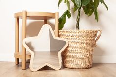 a star shaped wooden toy next to a basket with a plant in it on the floor