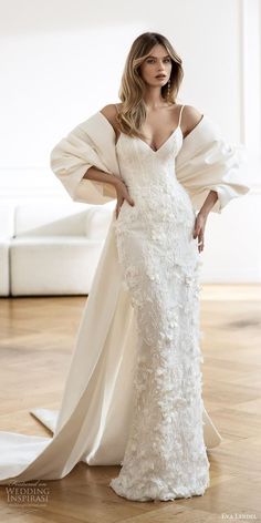 a woman in a white wedding dress standing on a wooden floor with her arms behind her back