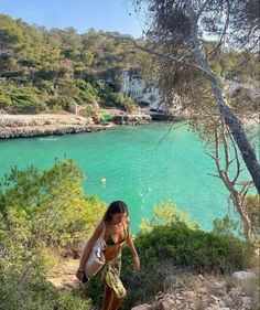 a woman walking up some steps near the water and trees in front of her is a body of water