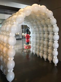 an arch made out of white balloons with a red fire hydrant