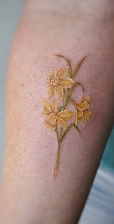 a close up of a person's arm with yellow flowers on the left side