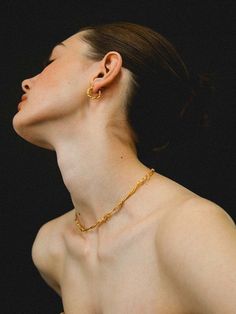 a woman wearing a gold necklace and earrings