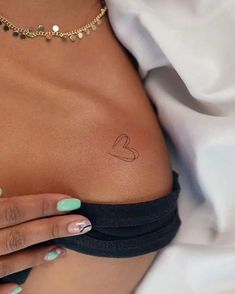 a woman's stomach with a small heart tattoo on it