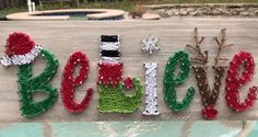 the word santa spelled out with string and bead on a piece of wood in front of a pool