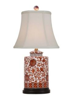 an orange and white vase lamp with a white shade on the top, sitting against a white background