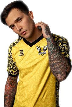 a man with tattoos on his arms and shoulder wearing a yellow shirt, looking at the camera