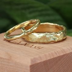 two gold wedding rings sitting on top of a wooden box