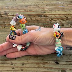 a person's hand holding several bracelets with cartoon characters on them