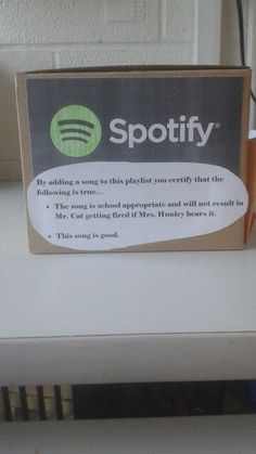 a spotify box sitting on top of a white table next to a blue cup