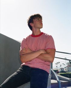 a young man sitting on the edge of a skateboard ramp with his arms crossed