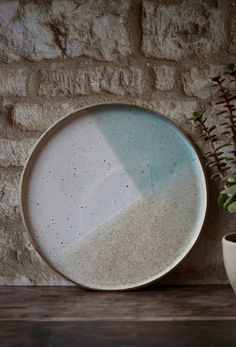 a white plate sitting on top of a wooden table next to a potted plant