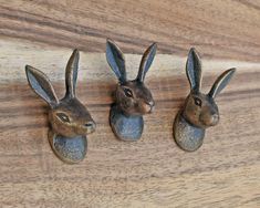 three metal rabbits sitting on top of a wooden table