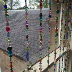 colorful beads hanging from the side of a window sill in front of a roof