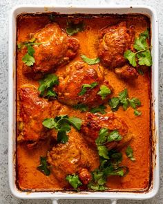 chicken curry in a white casserole dish with cilantro and parsley