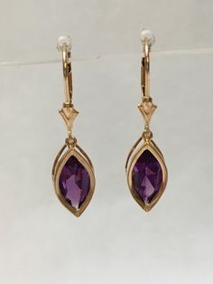 These beautiful amethyst were selected from a large collection of rough uncut amethyst that was brought to the United States from Zambia, Africa in 1986. Ken set these marquise cut stones in backset 14 K gold earrings with lever back. The dark African amethyst gemstones are 14mm x 7mm. and 1.8 caret total weight. Amethyst is the birthstone for February. Luxury Amethyst Dangle Earrings, Gold And Purple Earrings, Zambia Africa, Golden Earrings, Amethyst Gold, Purple Earrings, Oval Earring, Amethyst Earrings, Etsy Earrings Dangle