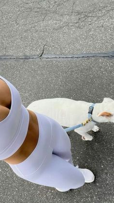 a woman in tights and heels walking her dog on a leash down the street