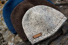 three knitted hats sitting on top of a rock