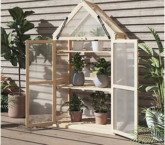 a house shaped greenhouse with potted plants in it