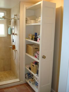 a walk in shower sitting next to a white sink under a bathroom window with towels on the shelves