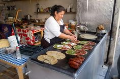 a woman cooking food on top of a grill in a kitchen next to other foods