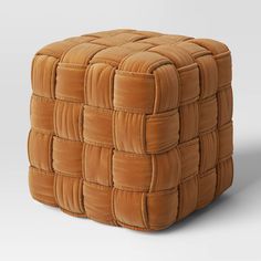 an ottoman made out of brown leather with squares on the top and bottom, sitting in front of a white background