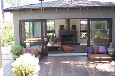 an outdoor living area with couches, table and fireplace in the back yard on a sunny day