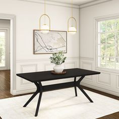 a dining room with white walls and wood flooring has a black table in the center