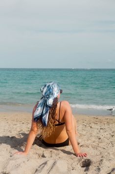 a woman sitting in the sand at the beach