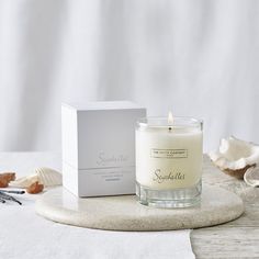 a candle sitting on top of a table next to a box and seashells