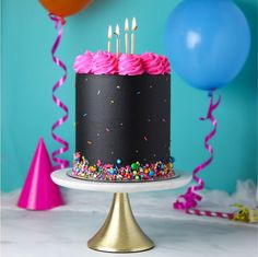 a birthday cake with pink frosting and sprinkles sits on a table