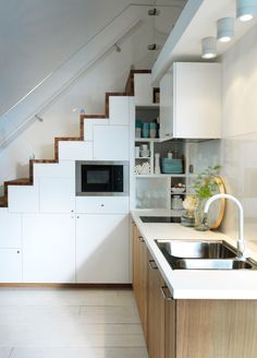 a kitchen with a sink, microwave and stairs leading up to the upper floor area