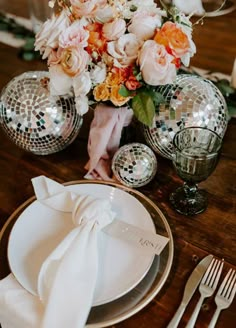 the table is set with flowers and disco ball plates, napkins and silverware