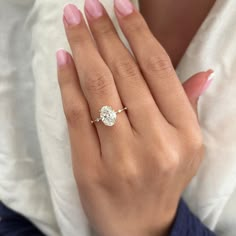 a woman's hand with a diamond ring on her left hand and pink nails