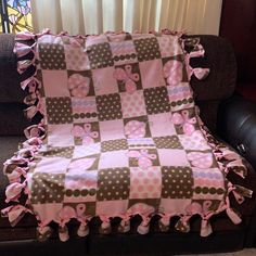 a pink and brown checkered blanket with polka dots on the edges is sitting on a couch