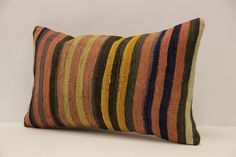 an orange and brown striped pillow sitting on top of a white table