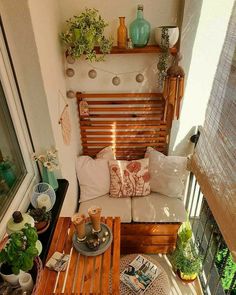 a small balcony with wooden furniture and potted plants on the windowsill, along with other outdoor decor