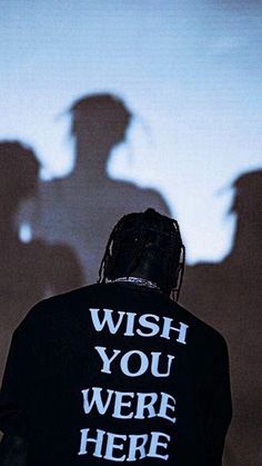 a man standing in front of a wall with the shadow of two people behind him