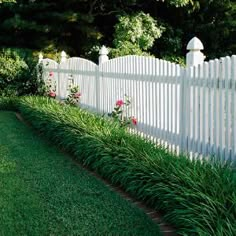 a white picket fence surrounded by lush green grass