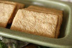 three pieces of cake sitting on top of a green tray next to a napkin and sprig of rosemary