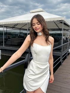 a woman in a short white dress standing on a dock