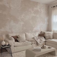 a living room with white couches and pillows on the floor next to a window