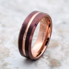 a wedding band with two tone gold and rose gold inlays, set on top of sand