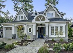 a white house with blue door and windows in the front yard, surrounded by trees