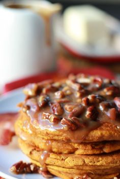 a stack of pancakes topped with nuts and caramel drizzled on top