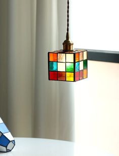 a multicolored light hanging from a ceiling fixture next to a book on a table