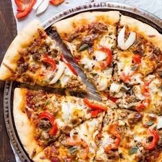 a pizza sitting on top of a pan covered in cheese and toppings next to sliced red peppers