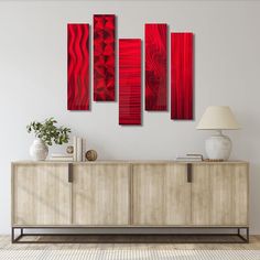 a red abstract painting on a wall in a living room with a lamp and sideboard