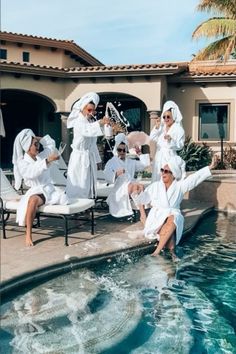 several people in white robes are sitting by the pool