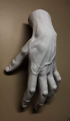 a white sculpture of a hand on a wall