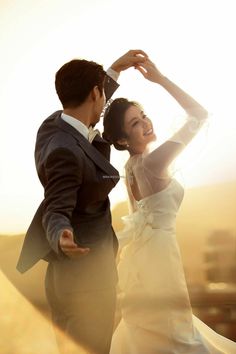 a bride and groom dancing together in the sun